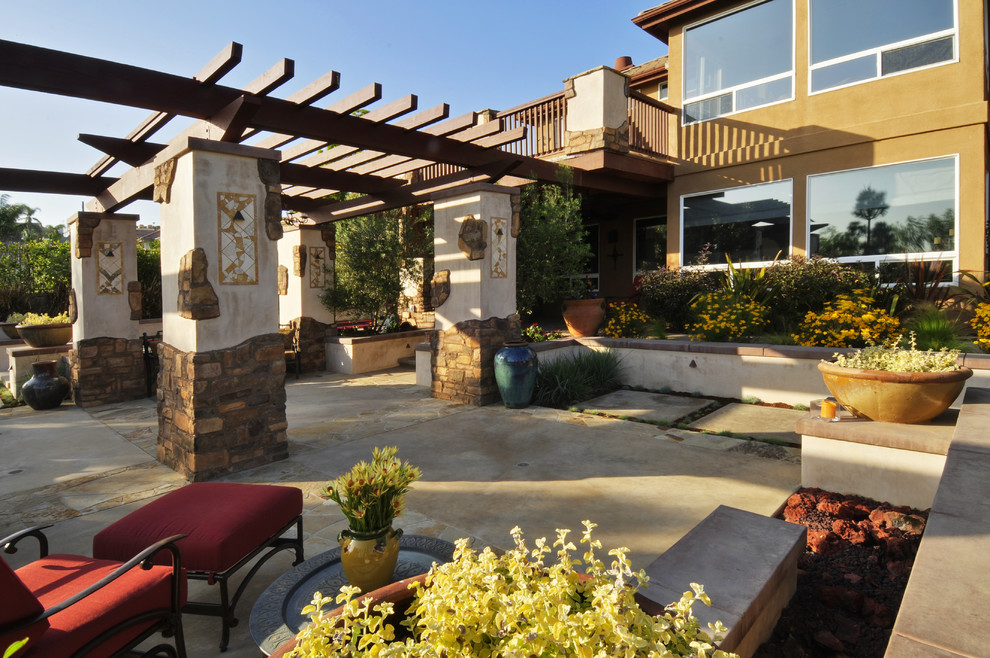 This is an example of a large mediterranean backyard patio in Orange County with concrete slab, a pergola and a fire feature.