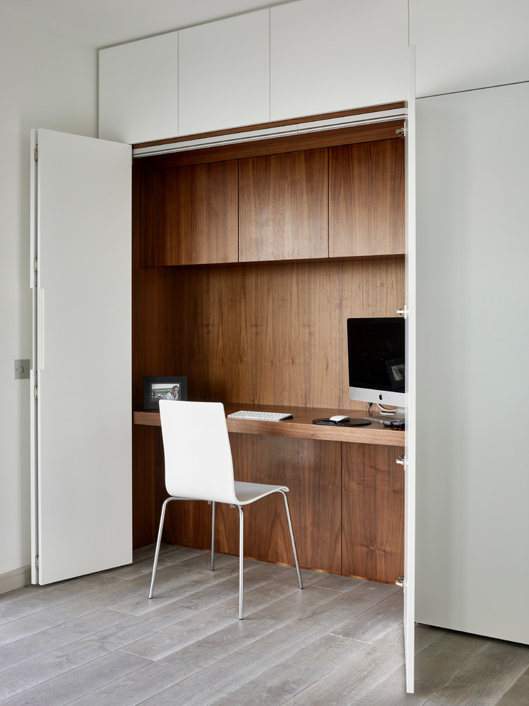 This is an example of a contemporary study room in London with a built-in desk, multi-coloured walls and light hardwood floors.