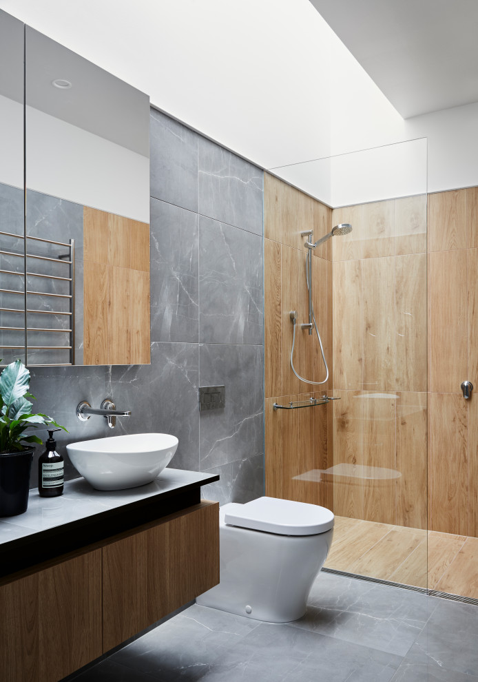 Inspiration for a contemporary bathroom in Melbourne with flat-panel cabinets, medium wood cabinets, an alcove shower, gray tile, white walls, a vessel sink, grey floor, an open shower and grey benchtops.