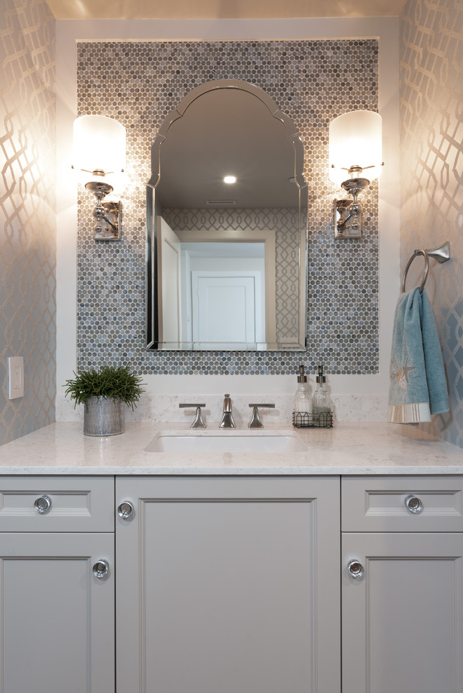 Inspiration for a small beach style master bathroom in Miami with recessed-panel cabinets, grey cabinets, a one-piece toilet, blue tile, mosaic tile, grey walls, marble floors, a drop-in sink, granite benchtops, grey floor and white benchtops.