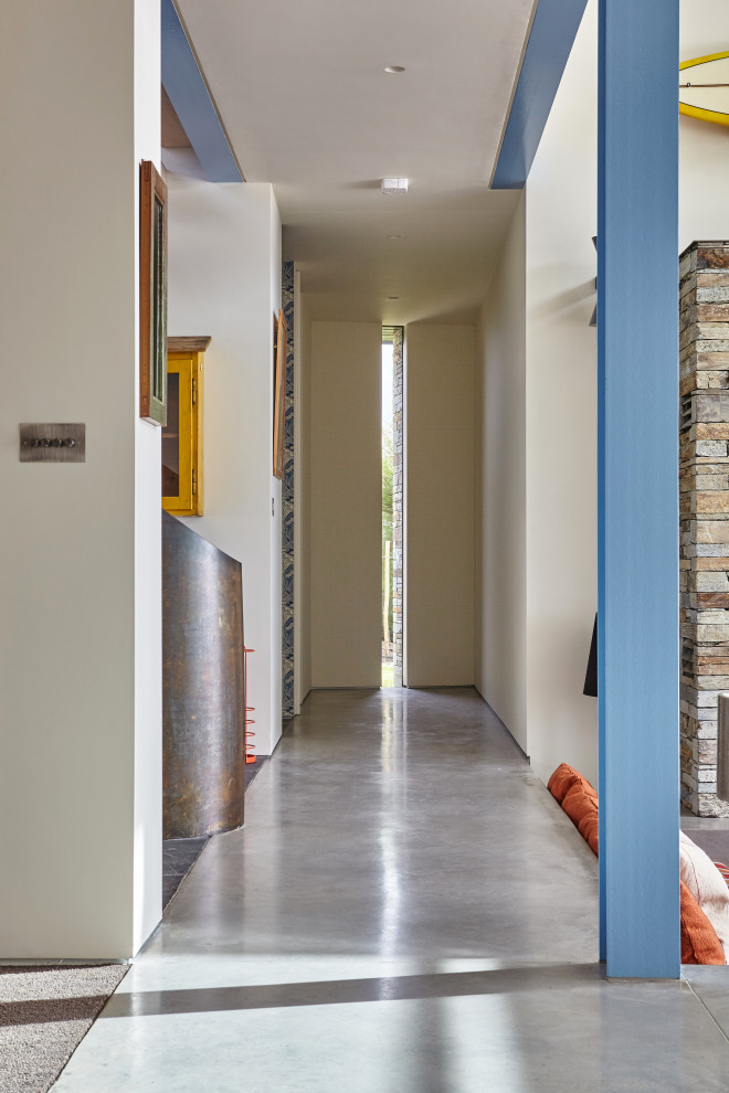 This is an example of a large contemporary hallway in Cornwall with white walls, concrete floors and grey floor.