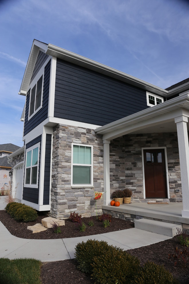 This is an example of a large arts and crafts two-storey blue exterior in Chicago with wood siding and a gable roof.