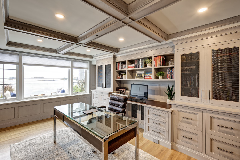 This is an example of a large beach style study room in New York with grey walls, light hardwood floors, a freestanding desk, brown floor, coffered and panelled walls.