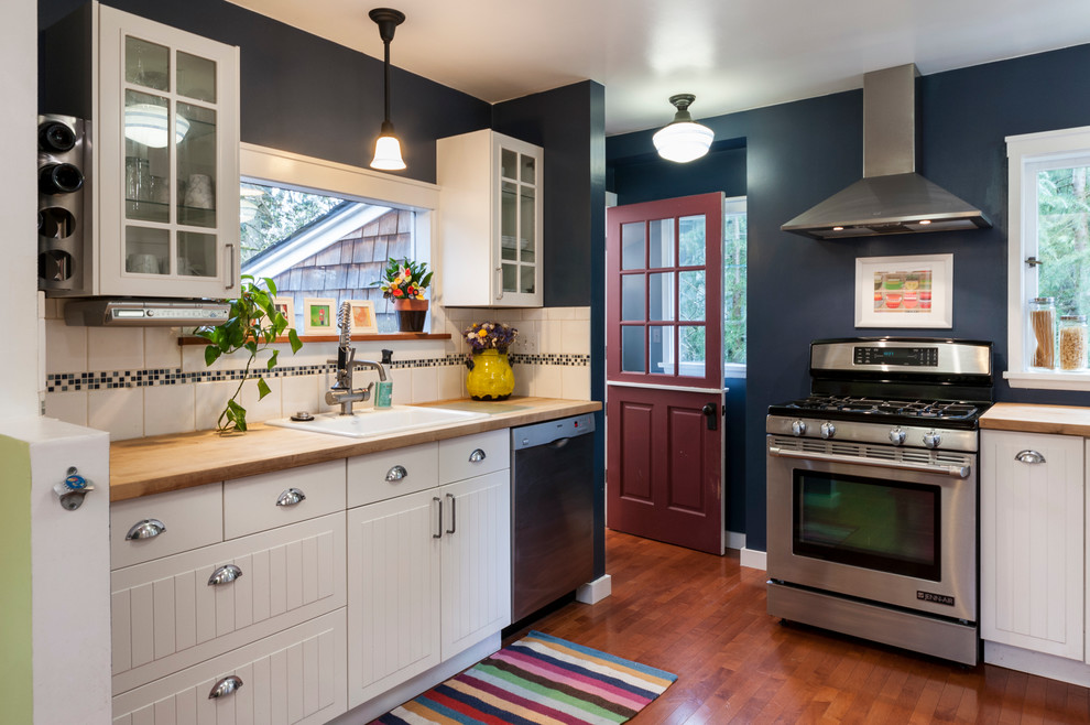 Photo of a country kitchen in Seattle with a drop-in sink, white cabinets, wood benchtops and dark hardwood floors.