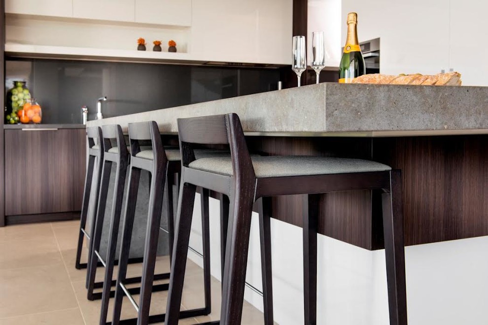 Eat-in kitchen - modern porcelain tile and beige floor eat-in kitchen idea with flat-panel cabinets, dark wood cabinets, concrete countertops, black backsplash, stone slab backsplash and an island