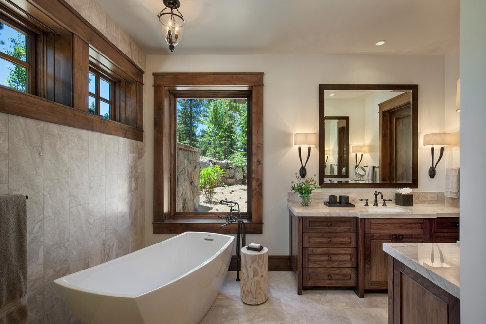 Design ideas for a country master bathroom in Sacramento with recessed-panel cabinets, dark wood cabinets, a freestanding tub, beige walls, an undermount sink, beige floor and beige benchtops.