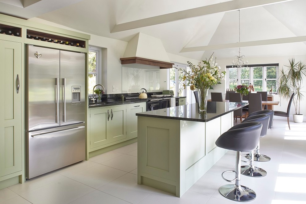 This is an example of a mid-sized transitional single-wall eat-in kitchen in Surrey with an undermount sink, shaker cabinets, green cabinets, granite benchtops, black splashback, glass sheet splashback, stainless steel appliances and with island.