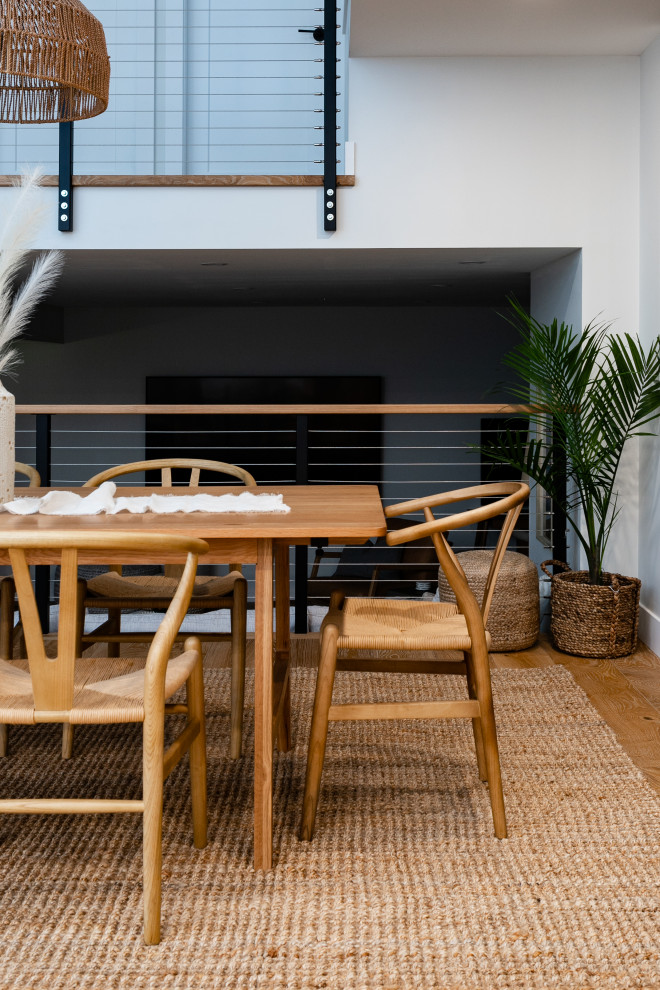Cette photo montre une grande salle à manger ouverte sur la cuisine scandinave avec un mur gris, un sol en bois brun et un sol marron.