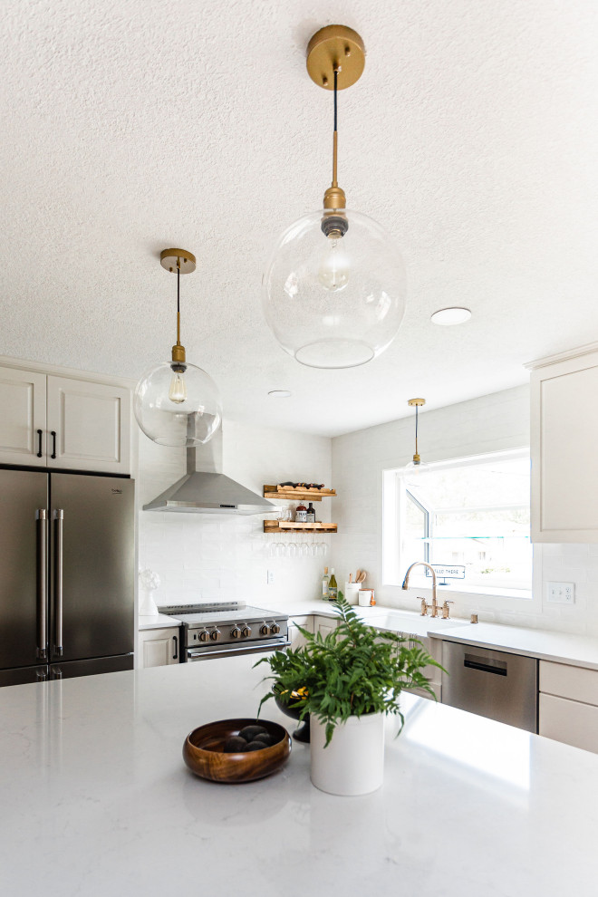 Example of a mid-sized 1960s l-shaped vinyl floor and beige floor eat-in kitchen design in Minneapolis with a farmhouse sink, raised-panel cabinets, white cabinets, quartz countertops, white backsplash, porcelain backsplash, stainless steel appliances, an island and white countertops