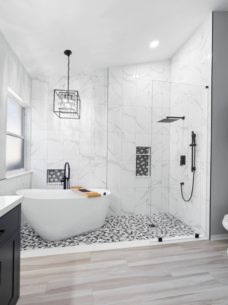Photo of a mid-sized modern master bathroom in Dallas with a built-in vanity, a freestanding tub, a shower/bathtub combo, marble, white walls, laminate floors, beige floor, a hinged shower door and a niche.