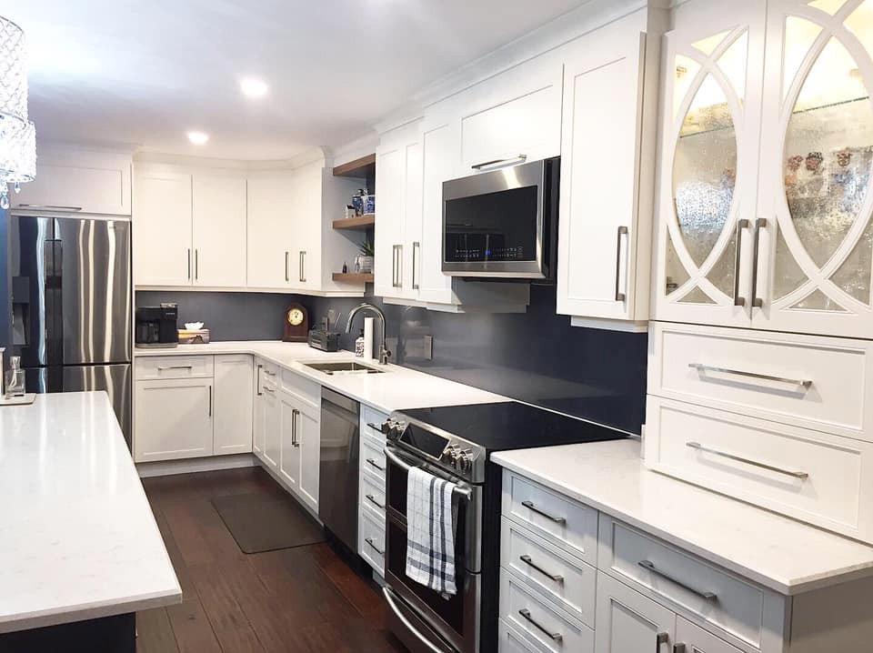 Inspiration for a mid-sized transitional l-shaped dark wood floor and brown floor eat-in kitchen remodel in Ottawa with an undermount sink, recessed-panel cabinets, white cabinets, quartz countertops, blue backsplash, quartz backsplash, stainless steel appliances, an island and white countertops