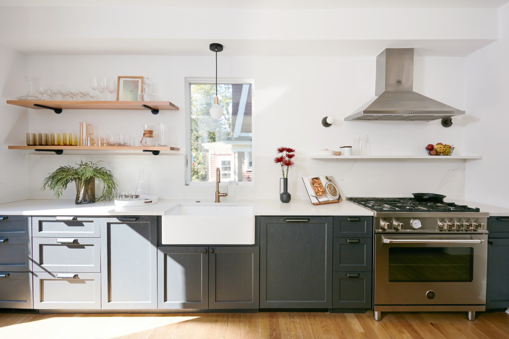 Inspiration for a mid-sized industrial eat-in kitchen in New York with a farmhouse sink, shaker cabinets, grey cabinets, quartz benchtops, white splashback, engineered quartz splashback, stainless steel appliances, light hardwood floors, a peninsula and white benchtop.