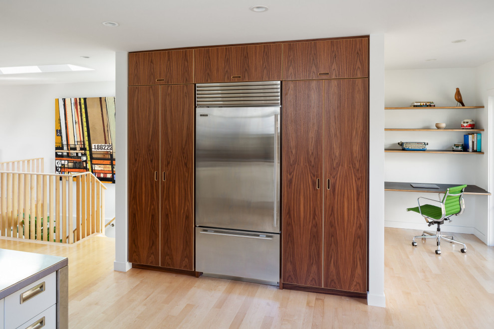 This is an example of a midcentury kitchen in San Francisco with dark wood cabinets, light hardwood floors, stainless steel appliances and grey benchtop.