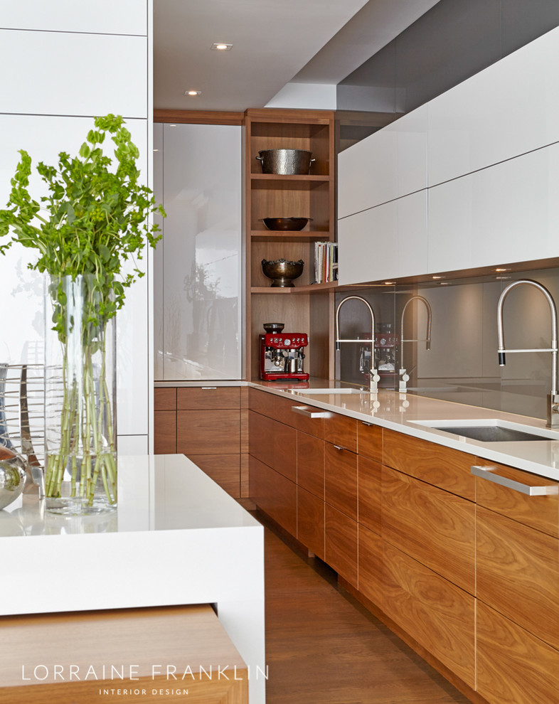 Design ideas for a large modern l-shaped open plan kitchen with white cabinets, grey splashback, glass sheet splashback, panelled appliances, with island, an undermount sink, flat-panel cabinets, quartz benchtops, concrete floors, brown floor and white benchtop.