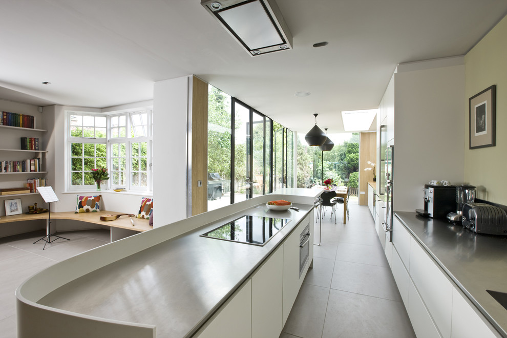 Photo of a mid-sized contemporary single-wall eat-in kitchen in London with an undermount sink, flat-panel cabinets, white cabinets, stainless steel benchtops, stainless steel appliances, ceramic floors and with island.
