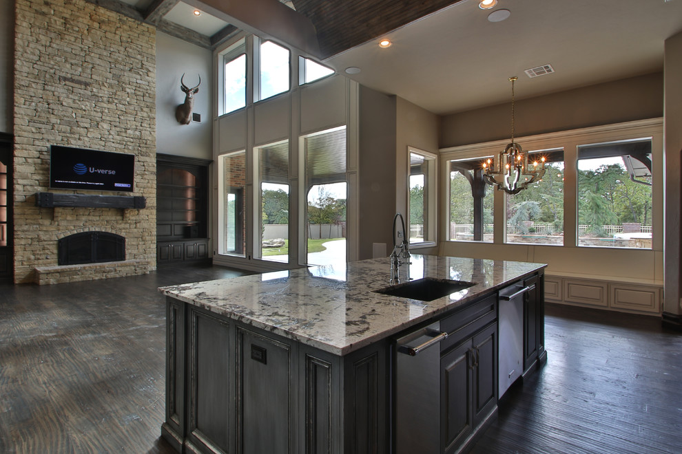 This is an example of a large country eat-in kitchen in Oklahoma City with dark wood cabinets, granite benchtops, glass tile splashback, stainless steel appliances, dark hardwood floors, with island and brown floor.