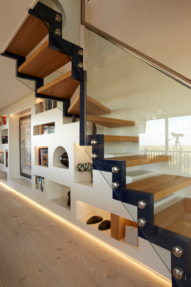 This is an example of a mid-sized beach style wood floating staircase in London with open risers.