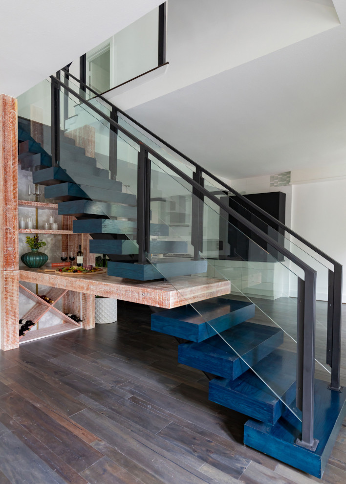 Design ideas for a mid-sized modern wood floating staircase in Houston with glass risers and metal railing.