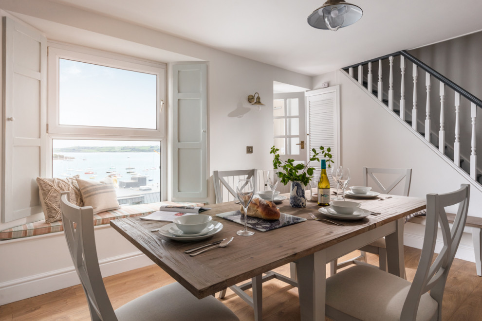 Mittelgroße Klassische Wohnküche mit weißer Wandfarbe, braunem Holzboden, Kaminofen, Kaminumrandung aus gestapelten Steinen und braunem Boden in Cornwall