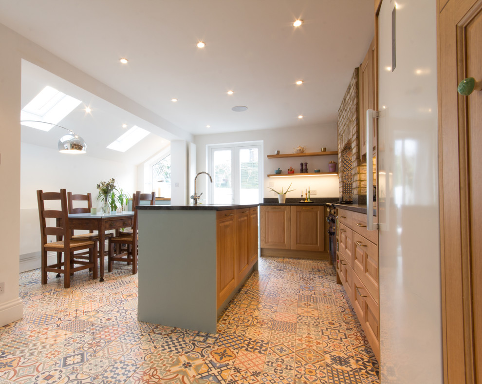 Photo of a large traditional l-shaped eat-in kitchen in London with a single-bowl sink, raised-panel cabinets, medium wood cabinets, quartzite benchtops, multi-coloured splashback, ceramic splashback, coloured appliances, porcelain floors and with island.