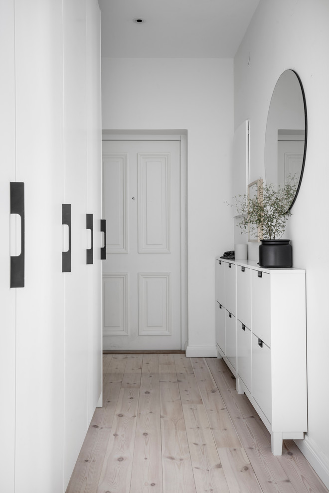 Design ideas for a scandinavian hallway in Gothenburg with white walls and light hardwood floors.
