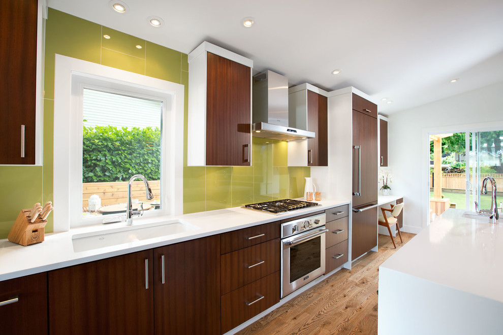 This is an example of a midcentury single-wall open plan kitchen in Vancouver with an undermount sink, dark wood cabinets, quartz benchtops, green splashback, panelled appliances and flat-panel cabinets.