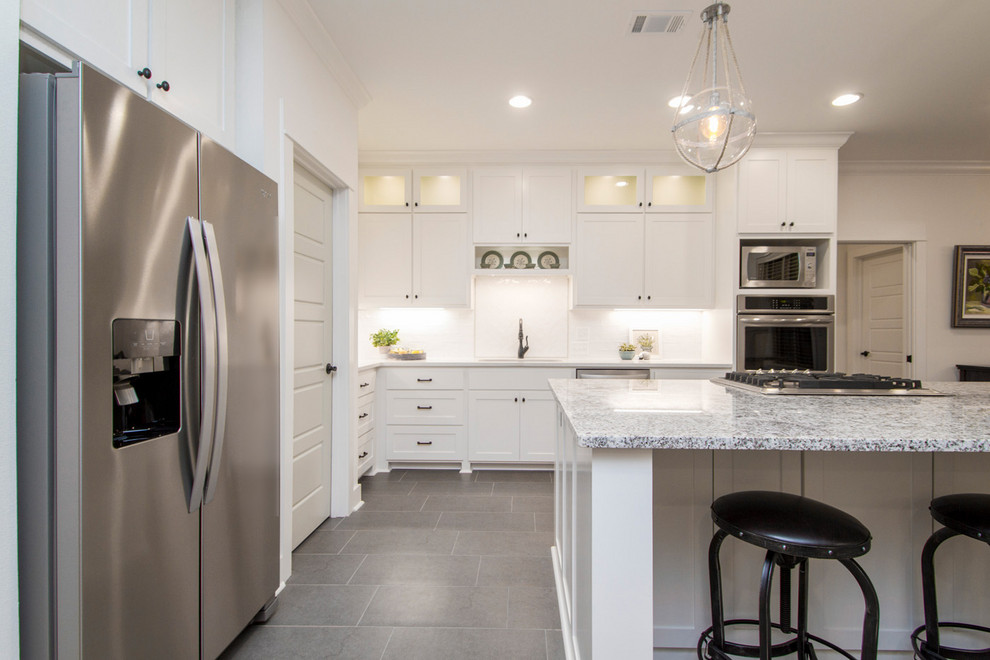 Inspiration for a transitional l-shaped open plan kitchen in Little Rock with an undermount sink, shaker cabinets, white cabinets, granite benchtops, white splashback, subway tile splashback, stainless steel appliances, porcelain floors, with island, grey floor and grey benchtop.