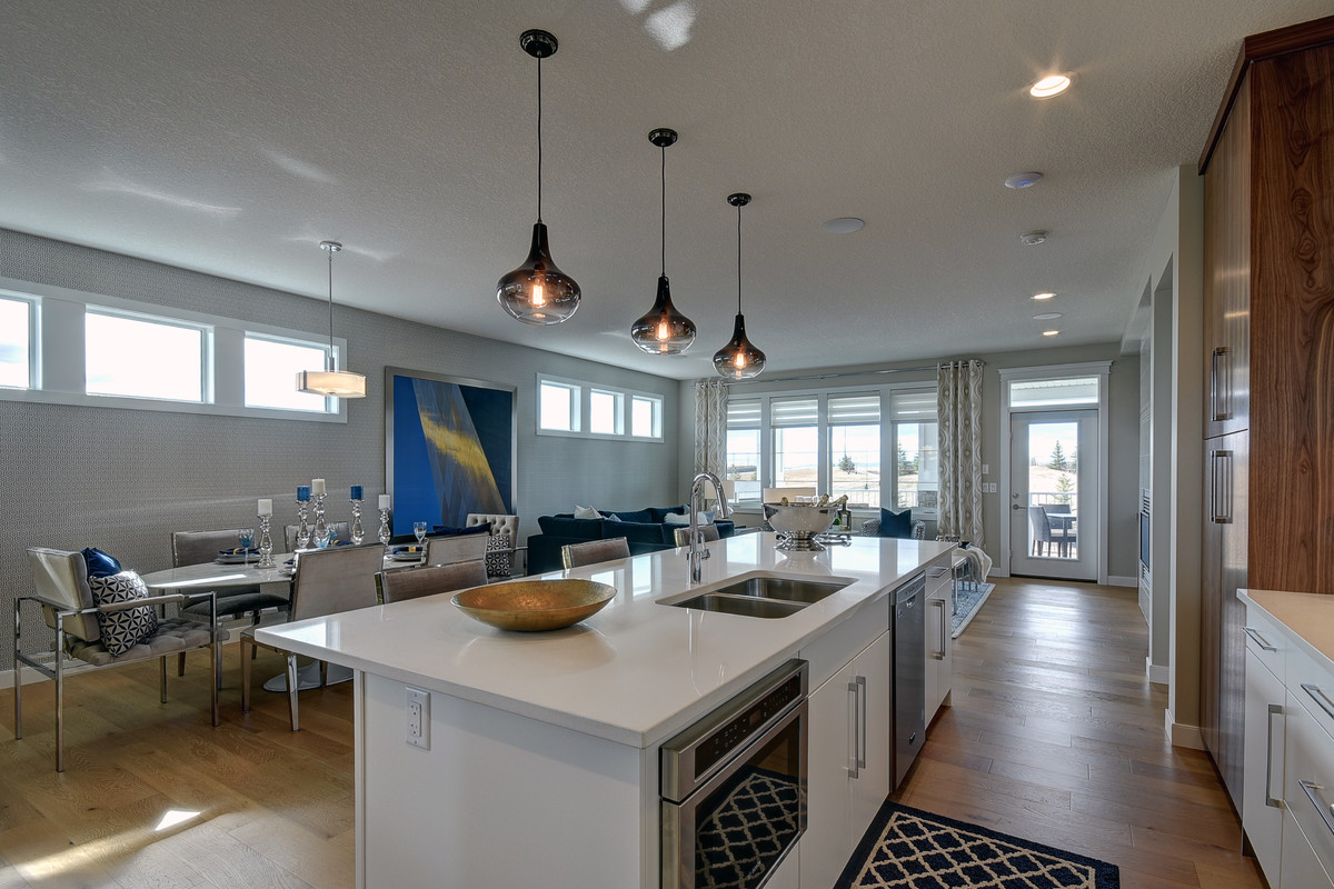 Mid-sized transitional single-wall light wood floor and beige floor enclosed kitchen photo in Calgary with an undermount sink, flat-panel cabinets, white cabinets, quartz countertops, white backsplash, stainless steel appliances, an island and marble backsplash
