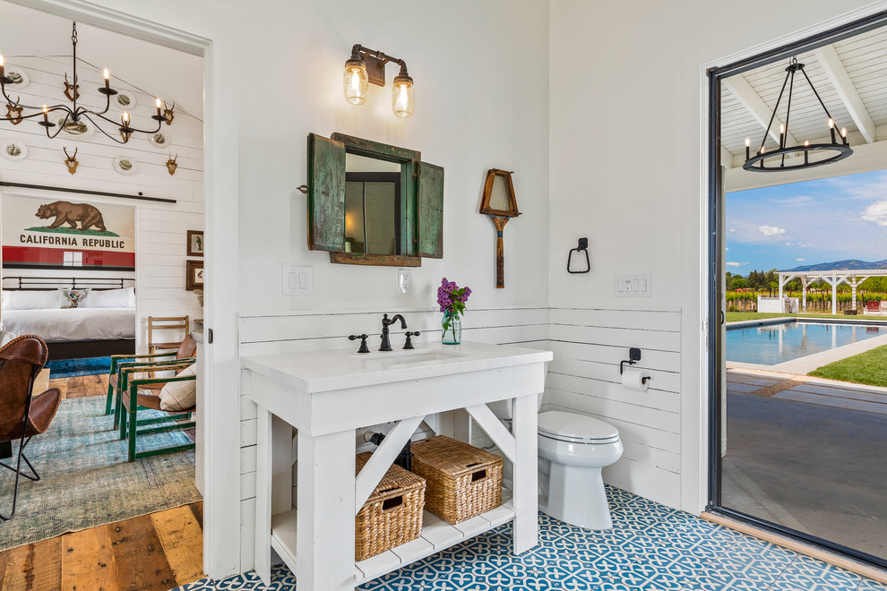 Design ideas for a country bathroom in San Francisco with open cabinets, white cabinets, white walls, an undermount sink, white benchtops and multi-coloured floor.