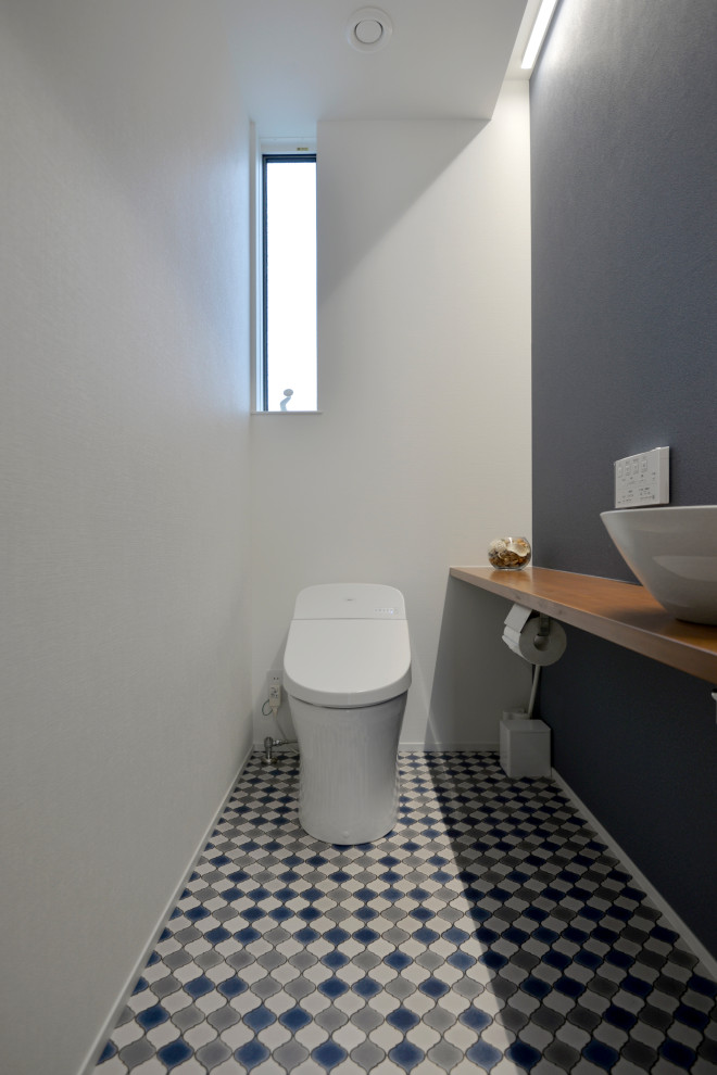 Medium sized scandinavian cloakroom in Other with open cabinets, medium wood cabinets, a one-piece toilet, white walls, vinyl flooring, a vessel sink, wooden worktops, blue floors, brown worktops, feature lighting, a built in vanity unit, a wallpapered ceiling and wallpapered walls.