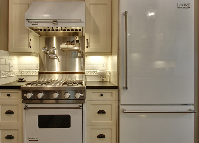 Photo of a traditional kitchen in Calgary with recessed-panel cabinets, beige cabinets, white splashback, subway tile splashback and white appliances.