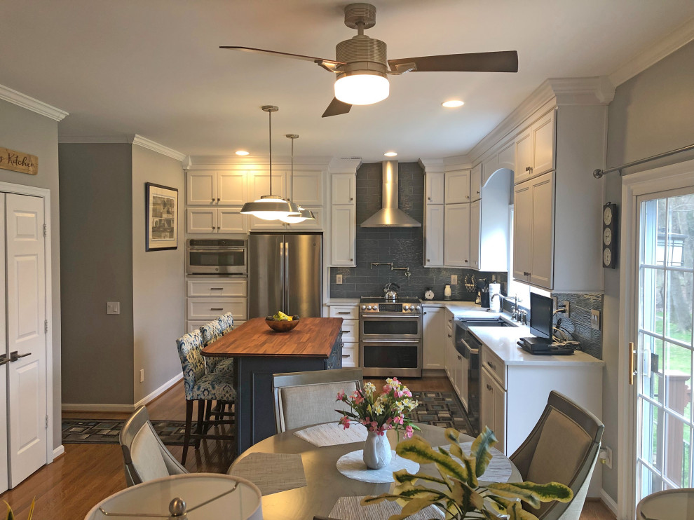 Design ideas for a large transitional l-shaped eat-in kitchen in DC Metro with a farmhouse sink, recessed-panel cabinets, white cabinets, quartz benchtops, blue splashback, glass tile splashback, stainless steel appliances, medium hardwood floors, with island, brown floor and white benchtop.