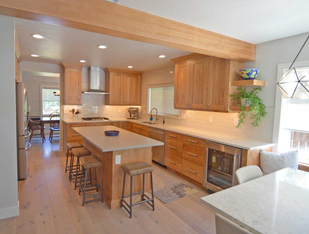 Mid-sized transitional u-shaped light wood floor, gray floor and exposed beam eat-in kitchen photo in Denver with an undermount sink, shaker cabinets, medium tone wood cabinets, quartz countertops, white backsplash, glass tile backsplash, stainless steel appliances, an island and multicolored countertops