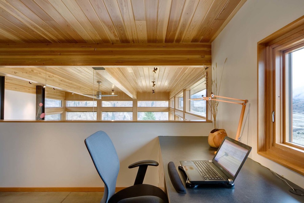This is an example of a contemporary home office in Seattle with white walls, concrete floors, a built-in desk and grey floor.