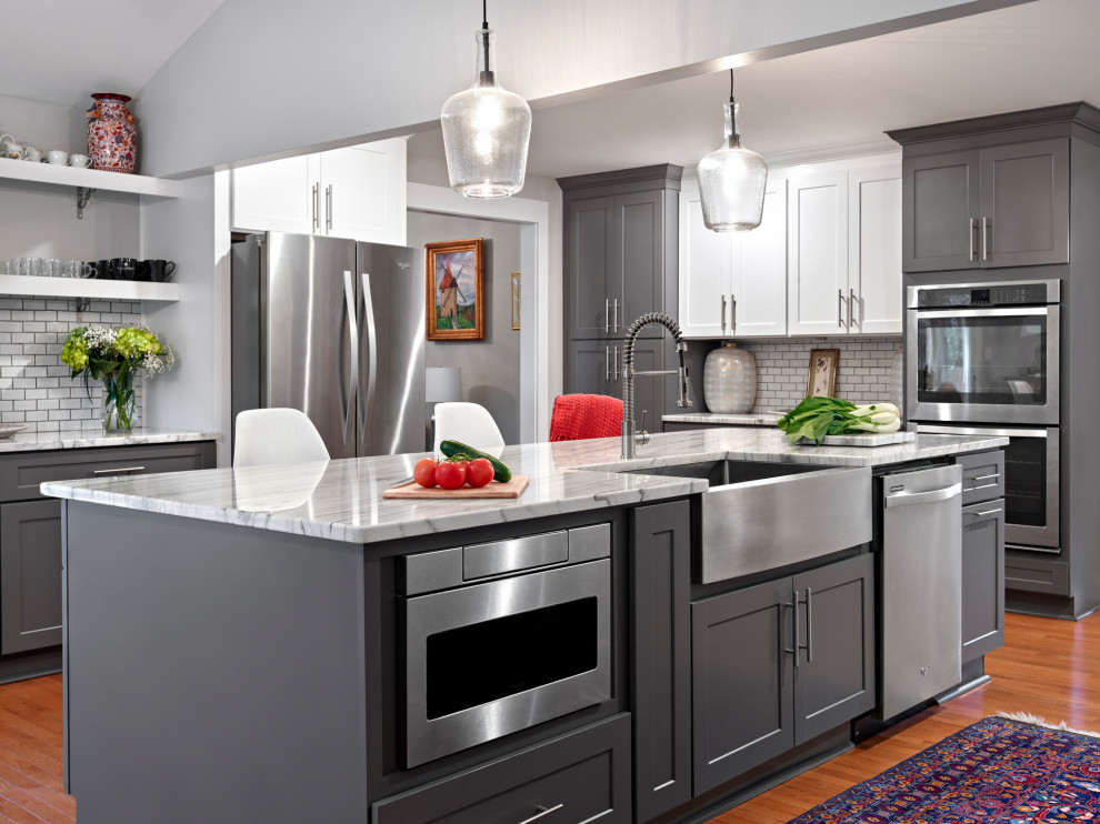 Kitchen - large transitional u-shaped medium tone wood floor and brown floor kitchen idea in Chicago with a farmhouse sink, shaker cabinets, gray cabinets, white backsplash, subway tile backsplash, stainless steel appliances, an island and gray countertops