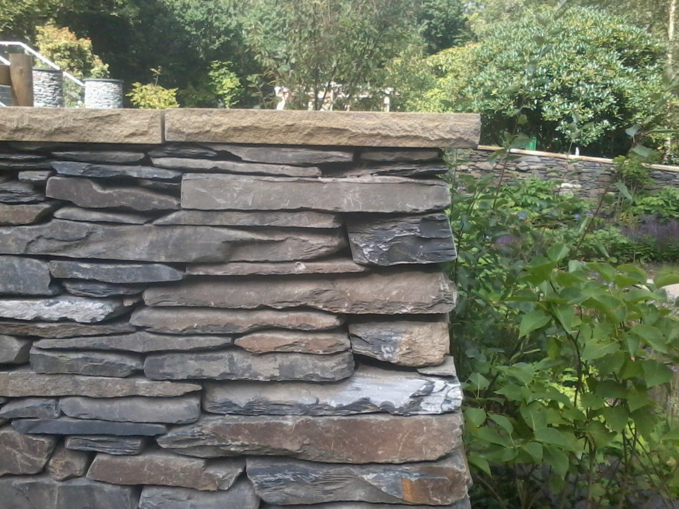 Esempio di un grande giardino formale classico dietro casa con un muro di contenimento, pavimentazioni in pietra naturale e recinzione in pietra