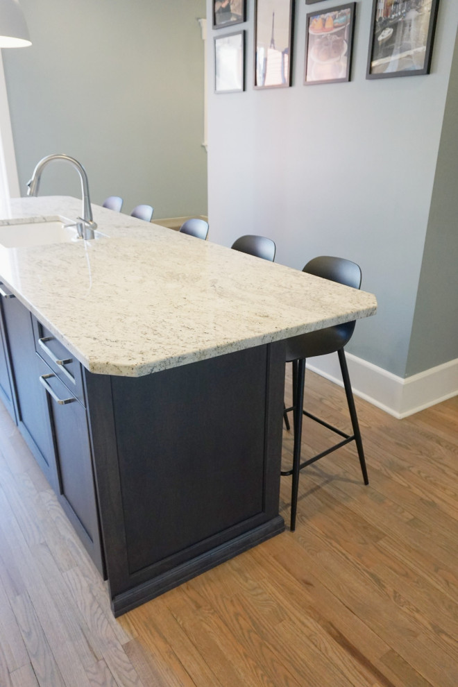 Inspiration for a huge transitional light wood floor and brown floor eat-in kitchen remodel with an undermount sink, shaker cabinets, white cabinets, granite countertops, white backsplash, ceramic backsplash, stainless steel appliances, an island and white countertops