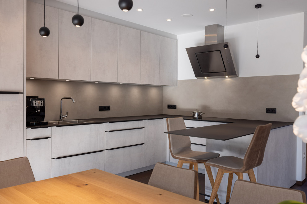 Mid-sized contemporary u-shaped open plan kitchen in Other with flat-panel cabinets, grey cabinets, solid surface benchtops, grey splashback, ceramic splashback, black appliances, a peninsula, black benchtop, a double-bowl sink, dark hardwood floors and brown floor.