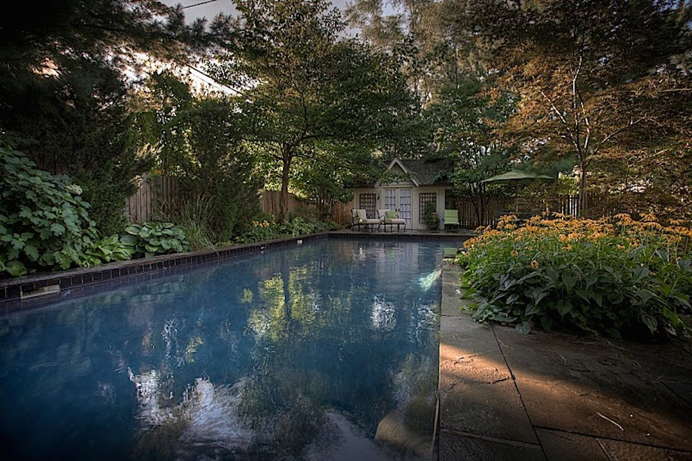 This is an example of a large transitional backyard l-shaped natural pool in Toronto with a pool house and natural stone pavers.