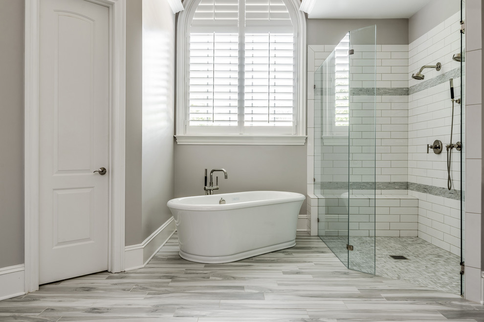Design ideas for a large transitional master bathroom in Charlotte with grey cabinets, a freestanding tub, a curbless shower, gray tile, terra-cotta tile, grey walls, porcelain floors, an undermount sink, engineered quartz benchtops, grey floor, a hinged shower door and grey benchtops.