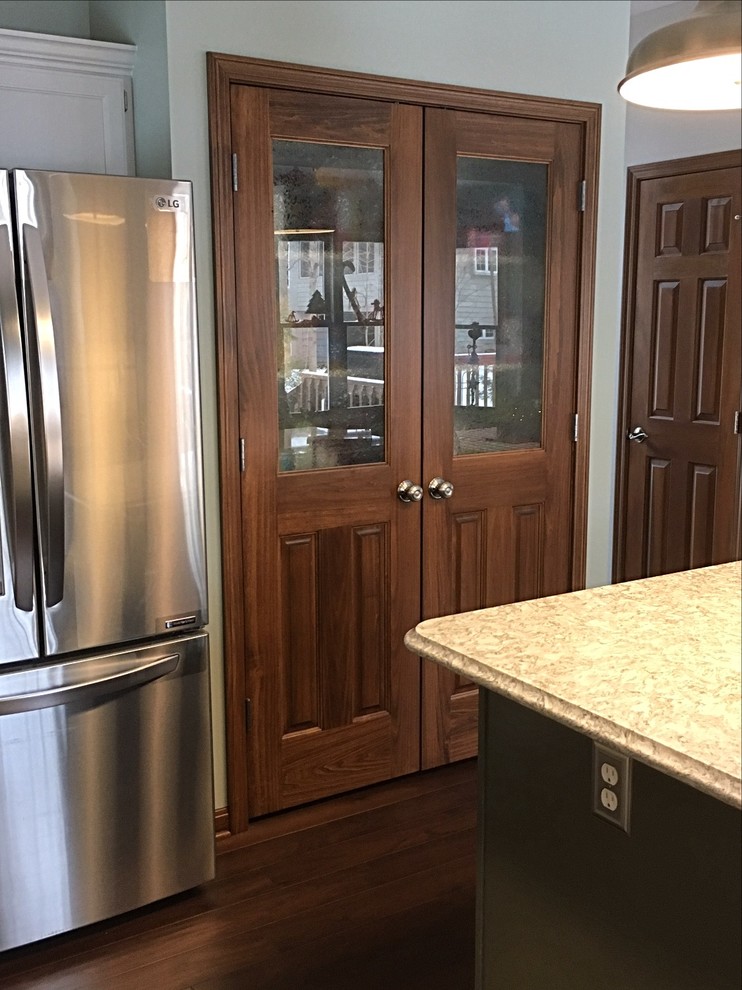 Mid-sized transitional u-shaped medium tone wood floor enclosed kitchen photo with an undermount sink, white cabinets, quartz countertops, white backsplash, subway tile backsplash, stainless steel appliances and an island