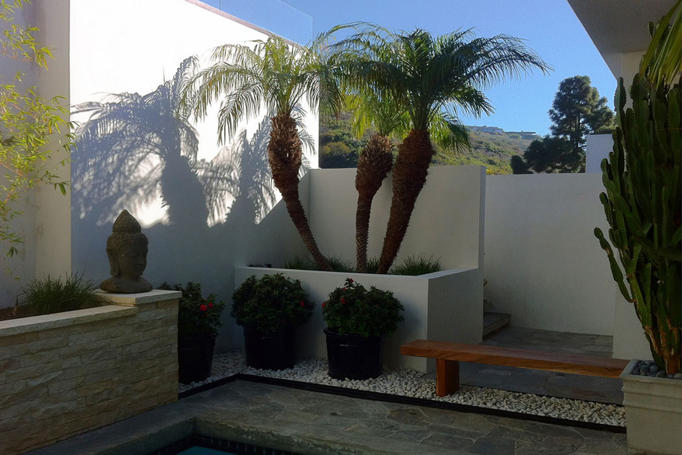 Mid-sized tropical sloped shaded garden in Orange County with natural stone pavers and a garden path.