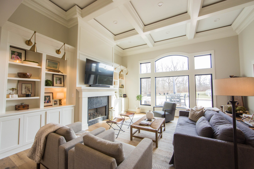Example of a large classic open concept medium tone wood floor, brown floor and coffered ceiling family room design in Indianapolis with beige walls, a standard fireplace, a tile fireplace and a wall-mounted tv