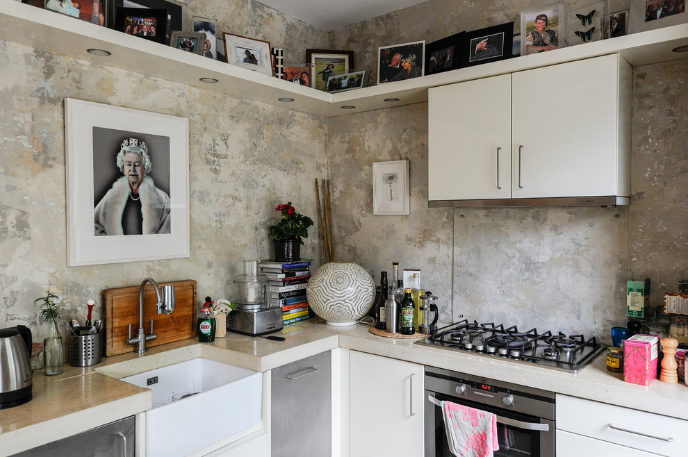 Inspiration for a small eclectic u-shaped eat-in kitchen in London with a peninsula, flat-panel cabinets, white cabinets, concrete benchtops, metallic splashback, stainless steel appliances and a farmhouse sink.