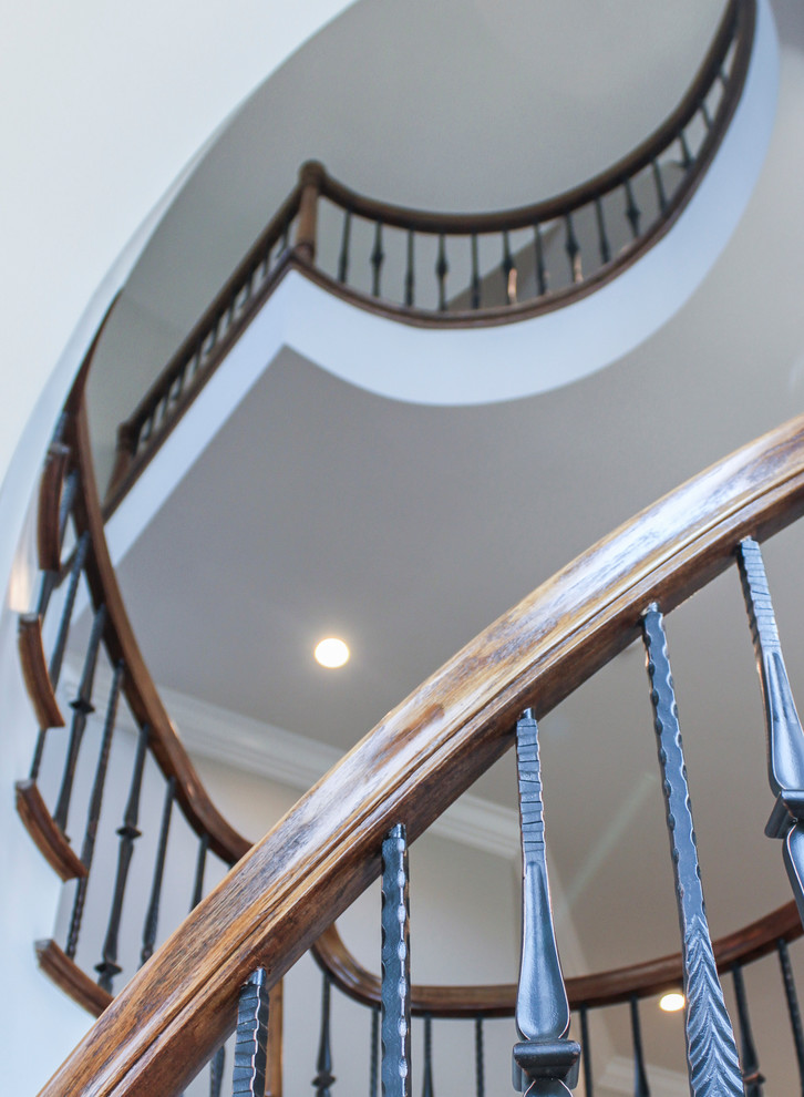 Large mediterranean wood curved staircase in DC Metro with wood risers and mixed railing.
