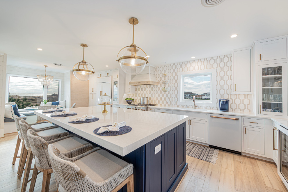 Inspiration for a large coastal single-wall vinyl floor and beige floor kitchen remodel in Other with an undermount sink, beaded inset cabinets, white cabinets, quartz countertops, white backsplash, marble backsplash, white appliances, an island and beige countertops