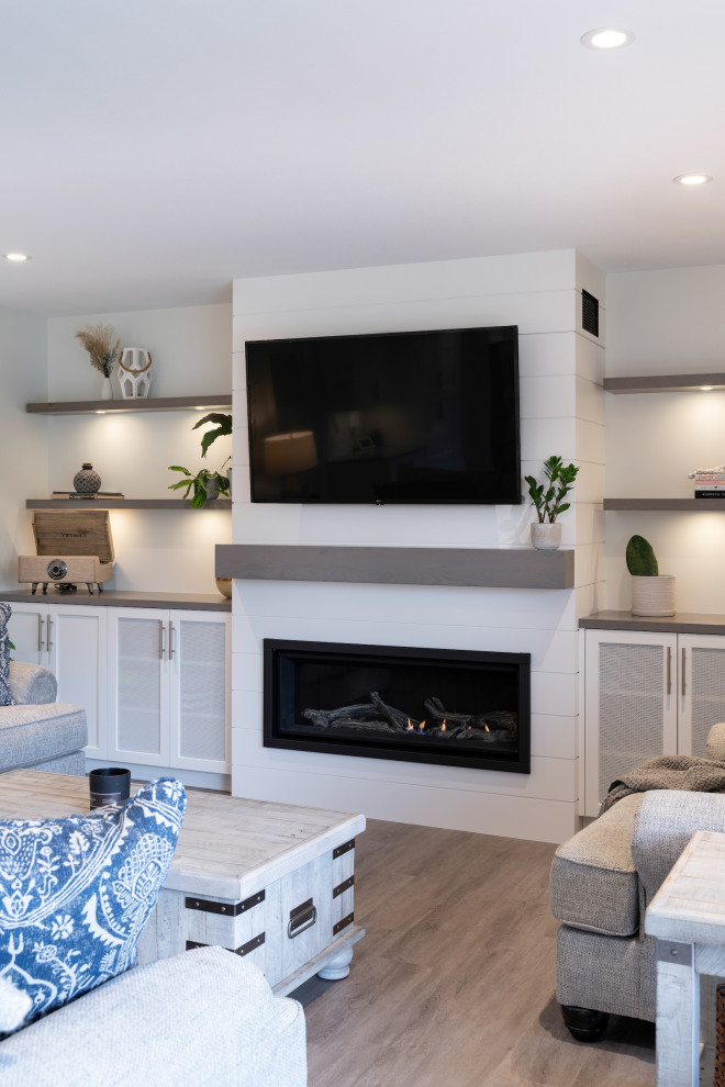 Large contemporary open concept living room in Vancouver with white walls, medium hardwood floors, a standard fireplace, a wood fireplace surround, a wall-mounted tv and grey floor.