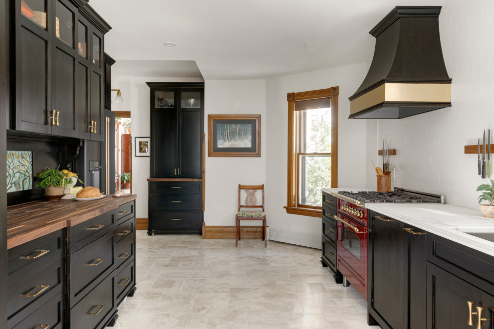 This is an example of a large traditional galley eat-in kitchen in Minneapolis with an undermount sink, shaker cabinets, black cabinets, wood benchtops, white splashback, subway tile splashback, coloured appliances, marble floors, no island, beige floor and brown benchtop.