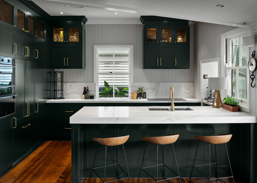 Inspiration for a transitional kitchen in Brisbane with an undermount sink, shaker cabinets, green cabinets, quartz benchtops, grey splashback, panelled appliances, medium hardwood floors, a peninsula, brown floor, multi-coloured benchtop, timber and vaulted.