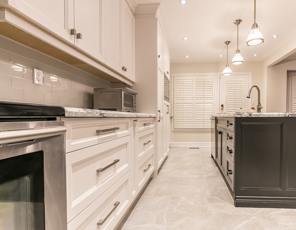 Enclosed kitchen - large transitional gray floor enclosed kitchen idea in Toronto with an undermount sink, recessed-panel cabinets, white cabinets, quartz countertops, white backsplash, ceramic backsplash, stainless steel appliances and an island